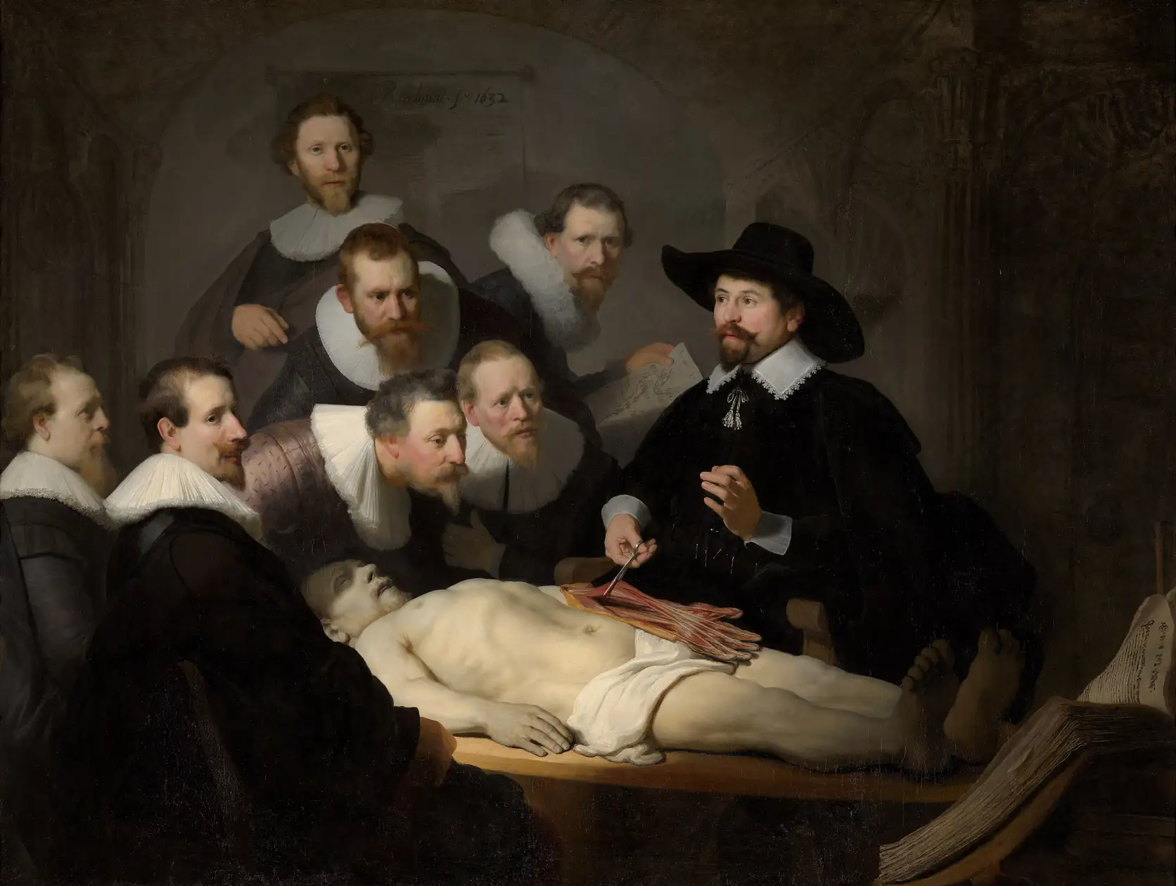 Surgeons gathered around a body as a doctor demonstrates the muscles of the arm